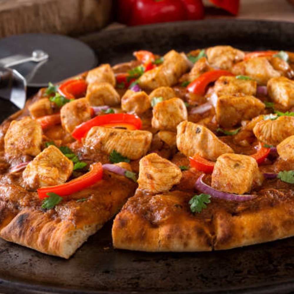 A delicious butter chicken pizza with red pepper, red onion and cilantro. A delicious butter chicken pizza with red pepper, red onion and cilantro.