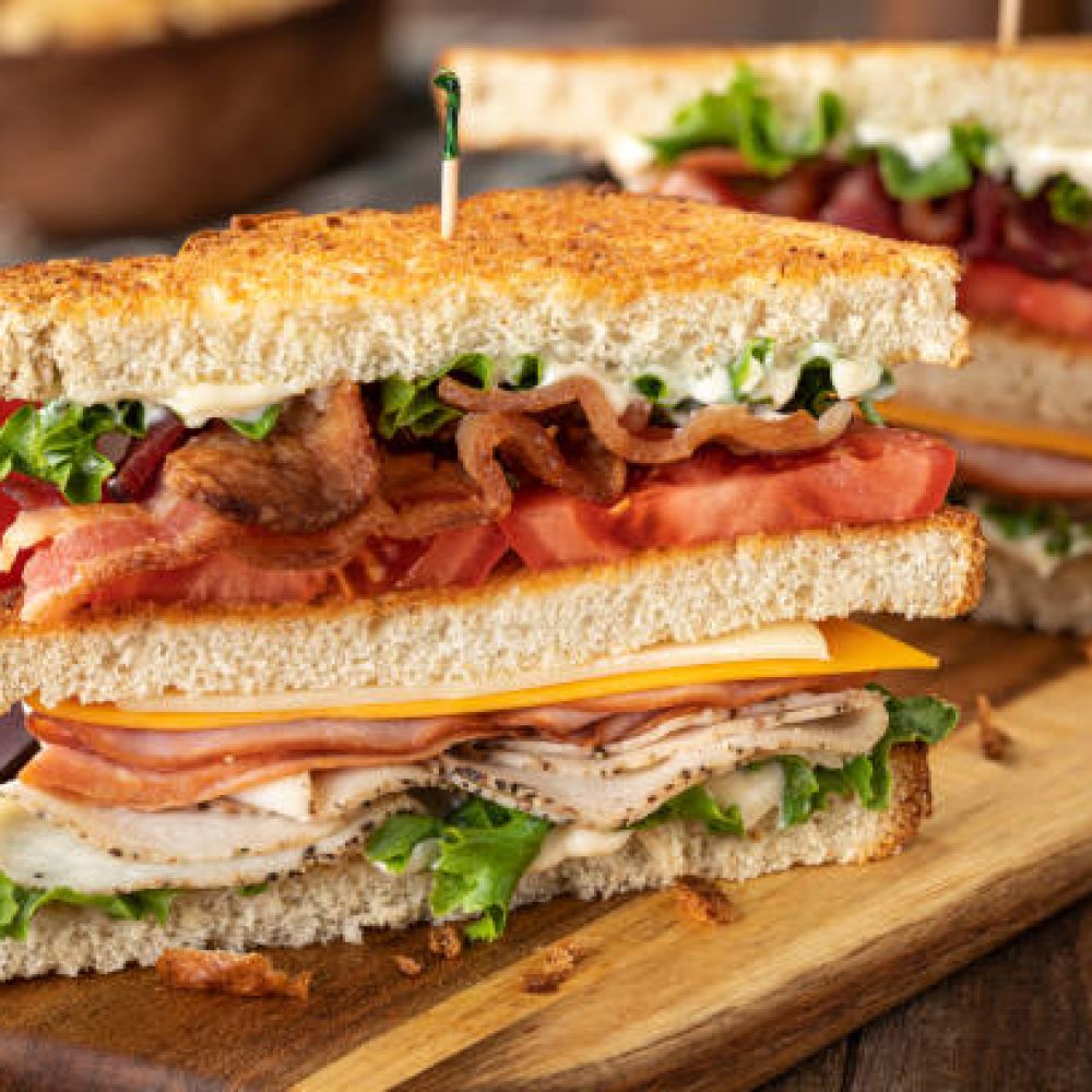 Club sandwich made with bacon, ham, turkey, cheese, lettuce and tomato on toasted bread