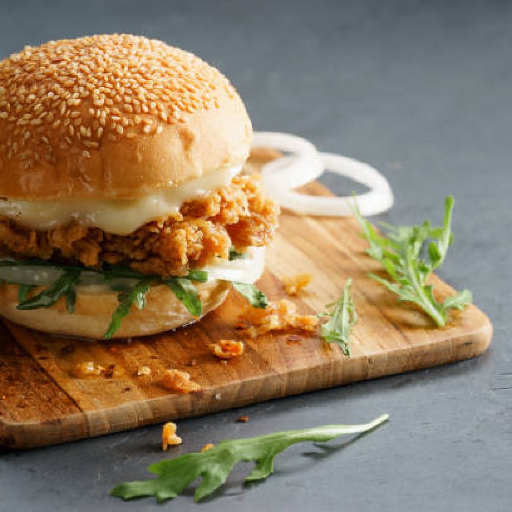 Tasty fired chicken with arugula and mayonnaise sauce served on wooden board Tasty fired chicken with arugula and mayonnaise sauce served on wooden board